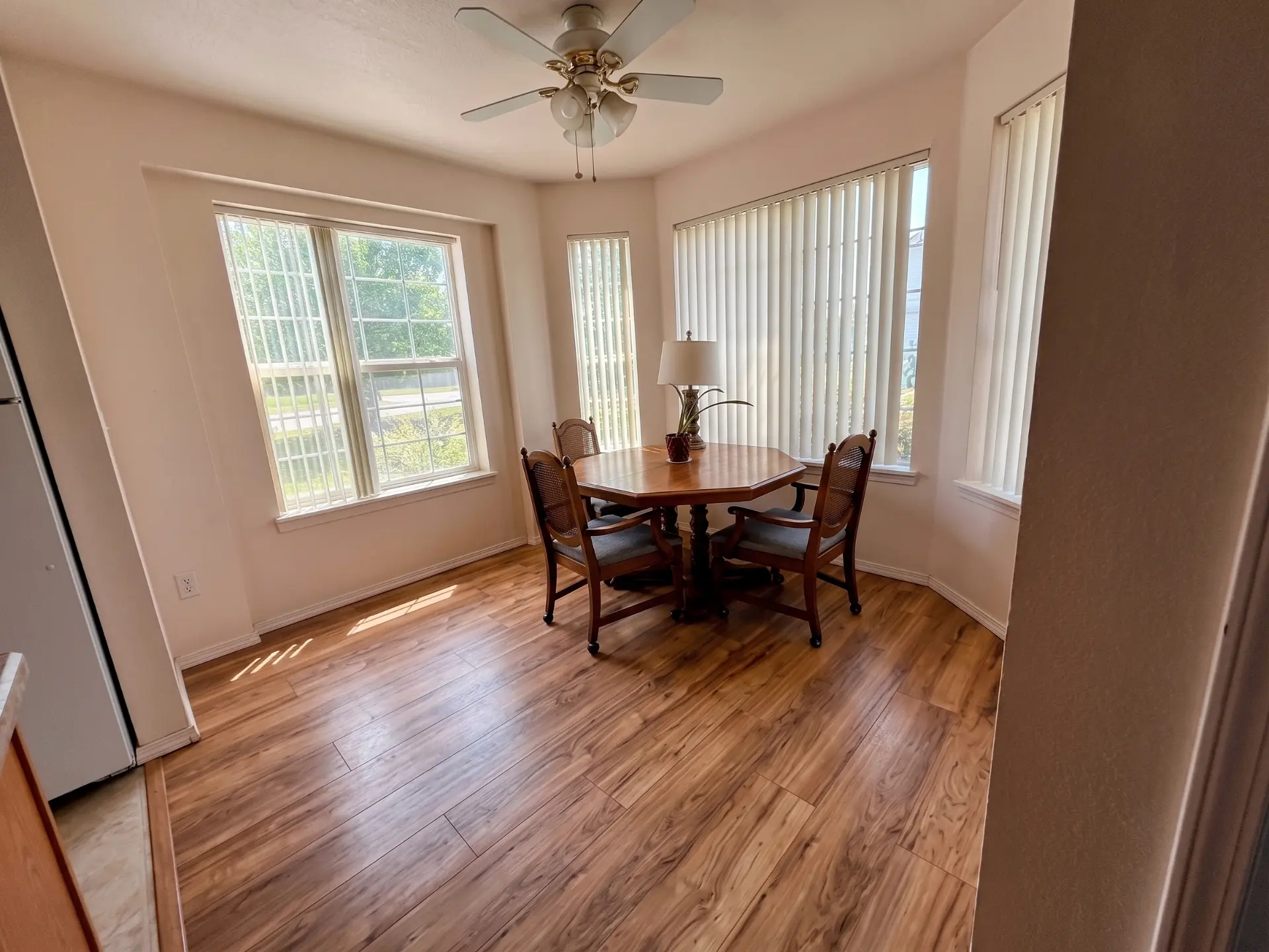 Dining area with a wood table and chairs, wood-look flooring, and large windows with blinds