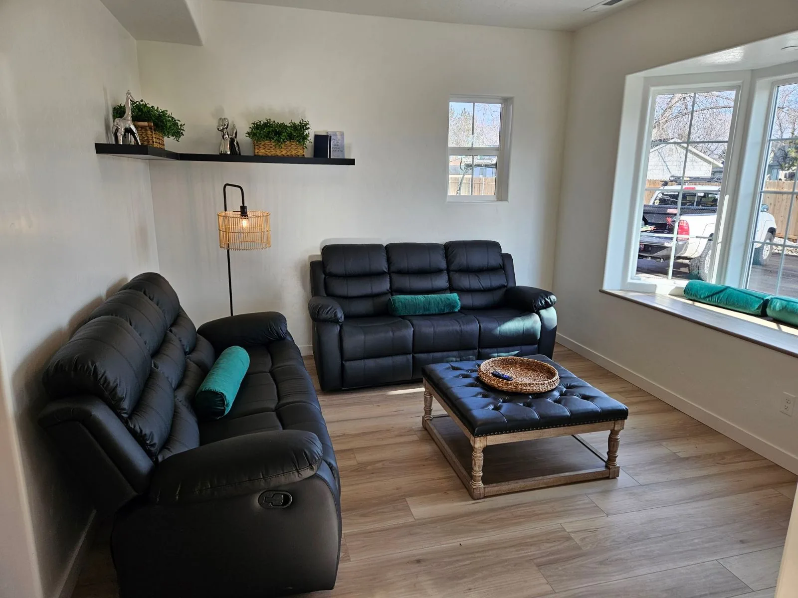 Rising Sun Sober Living home shared living room in Idaho with leather recliner sofas, floating shelf decor, and bright bay window