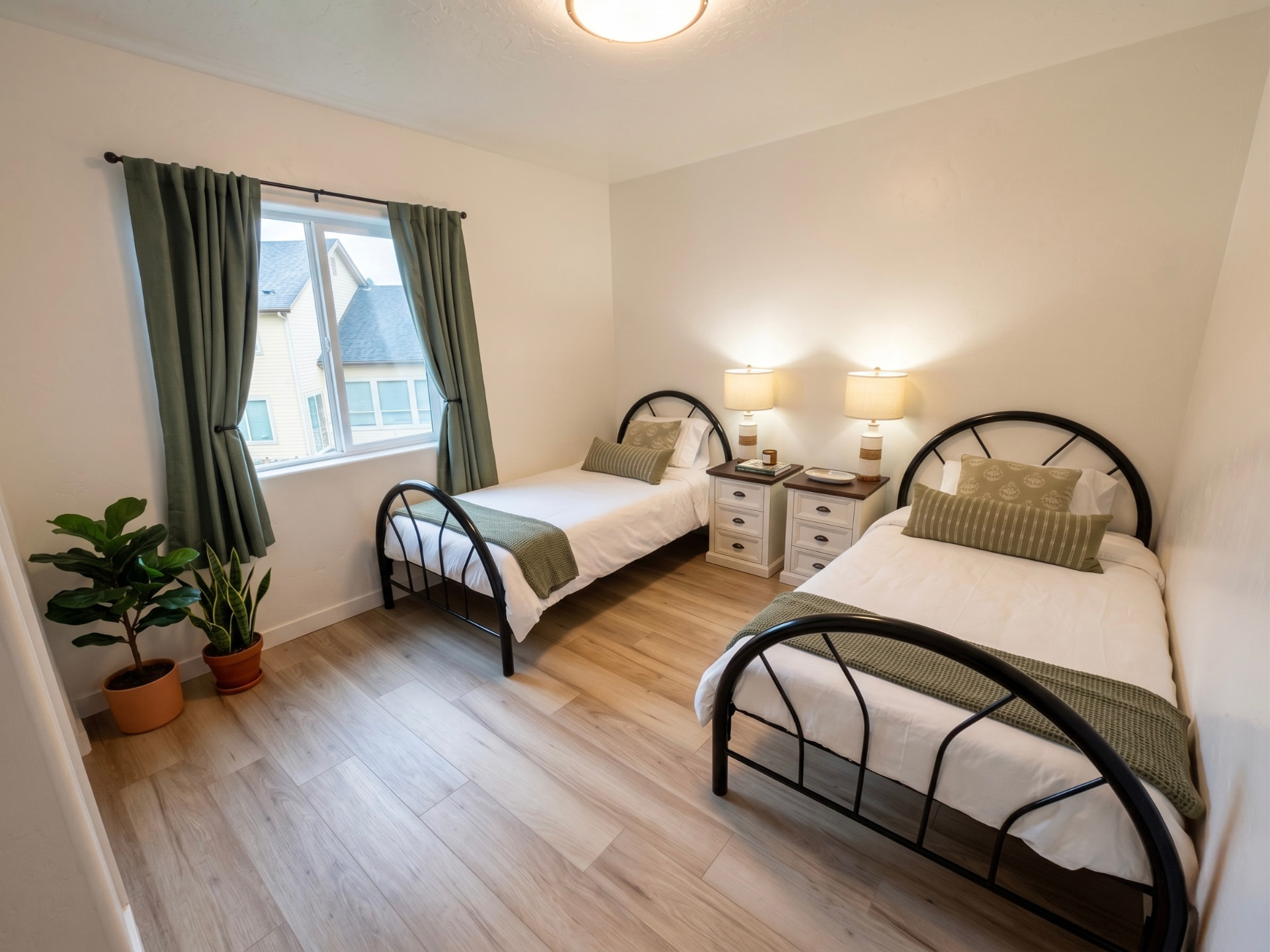 Rising Sun Boise resident bedroom with two twin beds, green accents, nightstand lamps, and window light